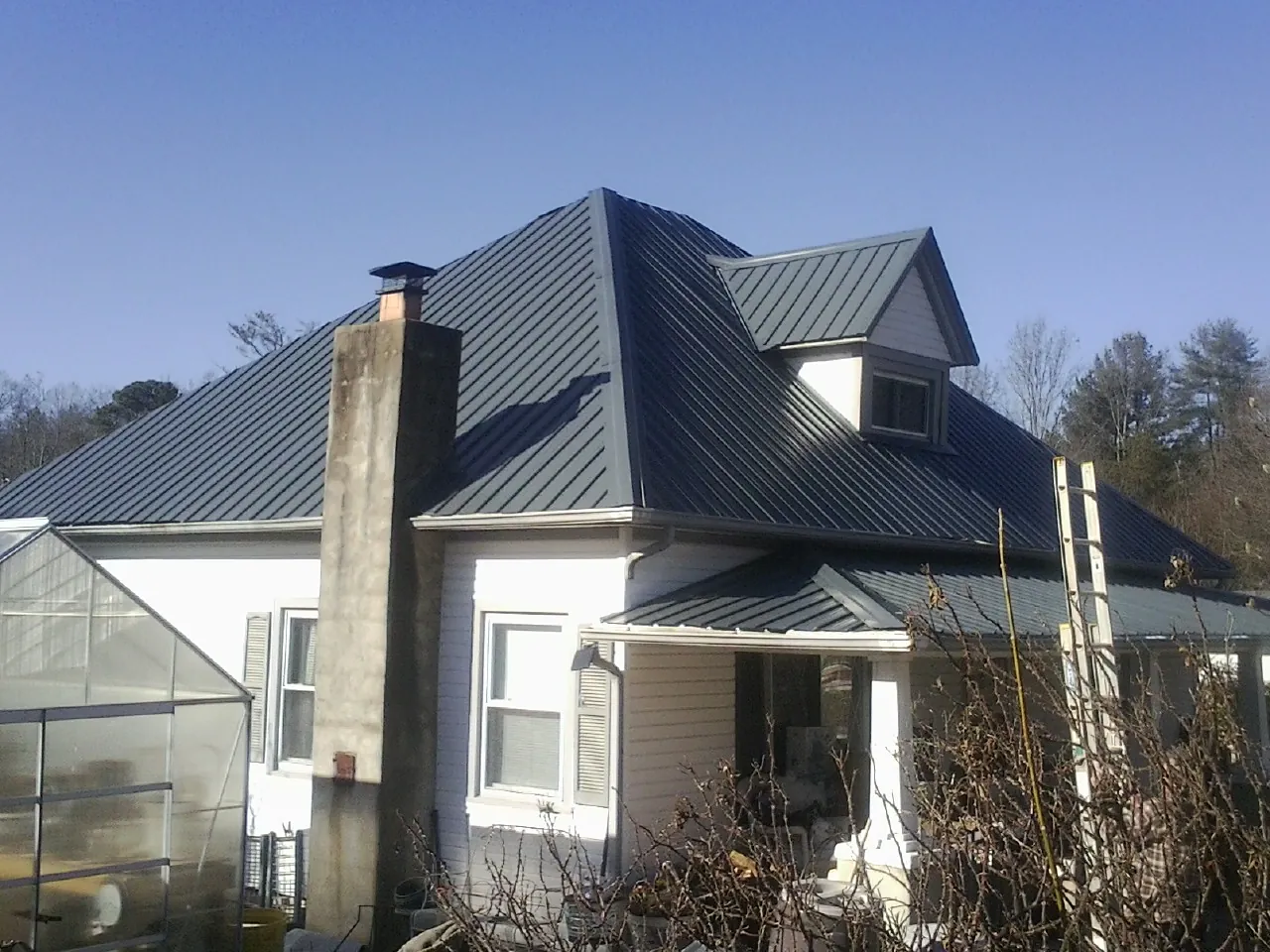 Dark blue standing seam metal roof on a white farmhouse with dormer — Slate & Tile Roof Repair by Roofing Brothers in Venice