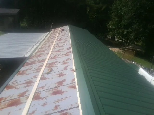 Old rusted panels beside newly installed green metal roofing — Wind Damage Roof Repair by Roofing Brothers in Venice