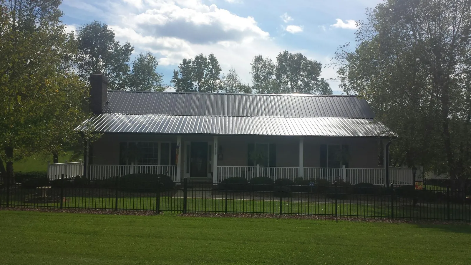Gray metal roof on a brick ranch with a full width front porch — Gutter Guard Installation work by our crew in Venice